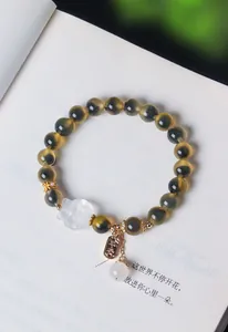 Nahaufnahme eines Armbands aus Zuckerherz-Achat mit weißem Kristallfuchs und Goldanhänger
