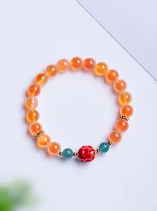 Gros plan détaillé des perles d'agate orange vif et d'une perle rouge sculptée à la main.