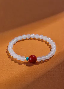 Gedetailleerd overzicht van de witte agaat kralenarmband met een rode en blauwe focuskraal.