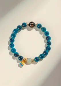 Dettaglio del bracciale di agata e giada con ciondolo a loto dorato e perla con scritte