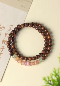 Close-up detail of natural sandalwood beads with translucent cat's eye stone accents.