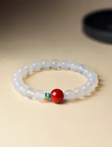 Detailopname van witte agaat kralenarmband met een rode accentkraal.