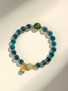 Primo piano di un bracciale in agata verde e giada con perla dorata e ciondolo a loto