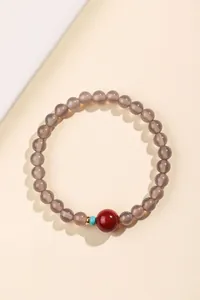 Close-up detail van de grijze agaat kralenarmband met een levendige rode kraal