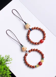 Detailed view of traditional lucky cat and cat paw charms on Bodhi wood bead phone straps
