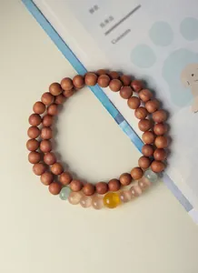 Close-up of green sandalwood prayer beads with yellow cat eye and aventurine stones.