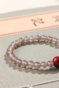 Macro-weergave van doorschijnende grijze agaat kralenarmband met rode accentkraal