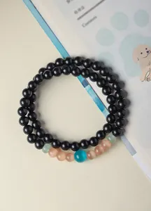 Detailed view of green sandalwood and cat's eye stone beaded bracelets.