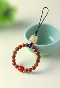 Detailed view of a Chinese-style bead pendant with a carved white lucky cat charm.