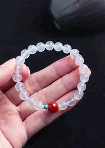 Gedetailleerd vooraanzicht van een doorschijnende witte agaat kralenarmband in hand