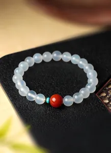 Gedetailleerde weergave van witte agaat kralenarmband met rode en turquoise kraal.