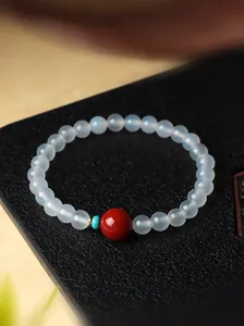 Detailopname van witte agaat kralenarmband met rode centrale steen in Chinese stijl
