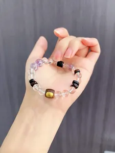 Detailaufnahme eines Kristall- und Adlerholz-Perlenarmbands mit goldener Gravur-Verzi