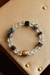 Nahaufnahme eines Armbands aus Bergkristall und schwarzem Rutilquarz auf Lederhintergrund.