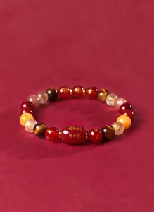 Gros plan d'un bracelet multi-pierres précieuses avec agate rouge et gravures bouddhistes