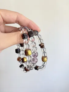 Detailansicht von Armbändern aus Bergkristall und Sandelholz mit goldenen Schriften.