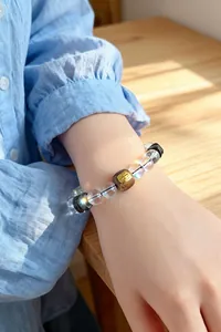 Nahaufnahme eines Armbands aus Bergkristall und Adlerholz am Handgelenk in Sonnenlicht