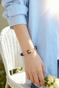 Detail eines Armbands aus Adlerholz und Kristallen am Handgelenk mit Goldgravur