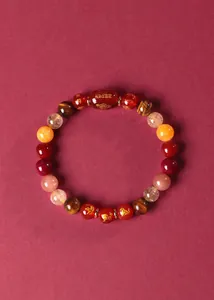 Gros plan d'un bracelet zodiaque multi-pierres avec agate rouge et perles gravées.