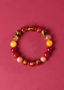 Détail d'un bracelet du zodiaque chinois en agate rouge avec des symboles dorés.