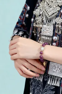 Nahaufnahme eines chinesischen Weihrauchperlen-Armbands mit Herzanhänger am Handgelenk.