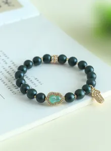 Detailansicht eines Armbands aus aromatischen Perlen mit vergoldetem Flaschenkürbis.