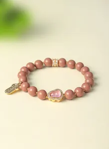 Detail eines Armbands aus natürlichen Räucherperlen mit goldenem Kürbis-Anhänger und Kristall