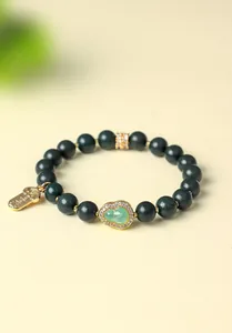 Detailansicht des dunkelgrünen Perlenarmbands mit goldenem Kürbis und Glücksanhänger