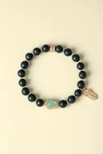 Detailansicht eines dunkelgrünen Perlenarmbands mit goldenem Anhänger und Kristallinlays.