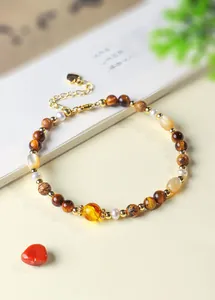 Detail van kralenarmband met tijgeroog, natuurlijke parels en barnsteen kraal