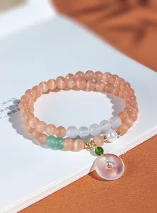Detaillierte Nahaufnahme eines zweireihigen Katzenaugen-Armbands mit Perlen und Jadeanhänger