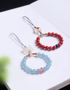 Detailansicht von roten und blauen Naturstein-Perlenanhängern für Taschen oder Handys.