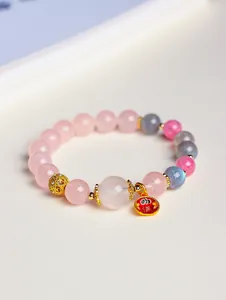 Detailansicht eines rosa und grauen Kristallperlenarmbands mit goldenen Anhängern
