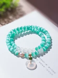 Detailansicht des zweilagigen Katzenaugenstein-Armbands mit Naturperle und Jade-Anhänger.