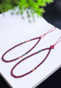 Detailed view of two garnet beaded charms on a white book with a blurred green background