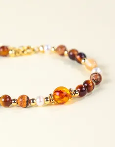 Gedetailleerd macrozicht van armband met zoetwaterparels, barnsteenhars en tijgeroogstenen