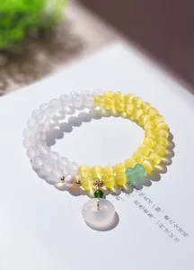 Detailansicht der gelben Katzenaugen-Perlen und des Ping'an Kou Anhängers am Doppelarmband.
