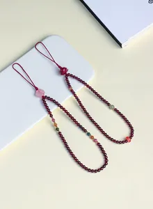 Macro view of deep red garnet beaded charms with delicate flower accents and koi motifs