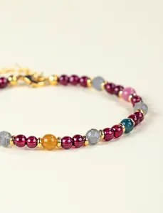 Nahaufnahme eines bunten Naturstein-Armbands aus Granat und Turmalin mit Goldakzenten