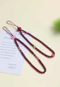 Detailed macro view of red garnet beaded charms with floral accents on a poetic card