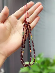 Detailed view of handmade garnet beaded charms with decorative floral and knot elements