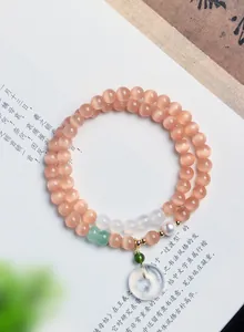 Nahaufnahme eines zweireihigen Katzenaugen-Steinarmbandes mit Perle und Donut-Anhänger