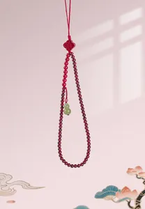 Detail view of a refined garnet beaded tassel with a green jade gourd charm for bags.
