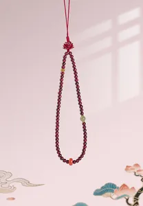 Exquisite close-up of a red garnet beaded hanging charm featuring a carved lotus and jade.