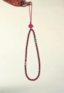 Detail view of garnet beaded pendant with a golden koi fish and green jade accents.