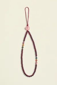 Detailed view of dark red pomegranate stone beaded strap with pink flower charm