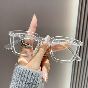 Vista detallada de elegantes gafas de lectura transparentes con montura cuadrada en la mano