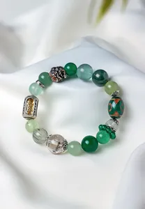 Detailed close-up of a green gemstone bracelet with Tibetan silver and gold charms