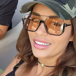 Close-up of oversized square sunglasses with a stylish double bridge on a female model.