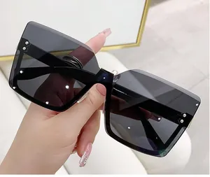 Occhiali da sole quadrati oversize senza montura con lenti sfumate scure in mano